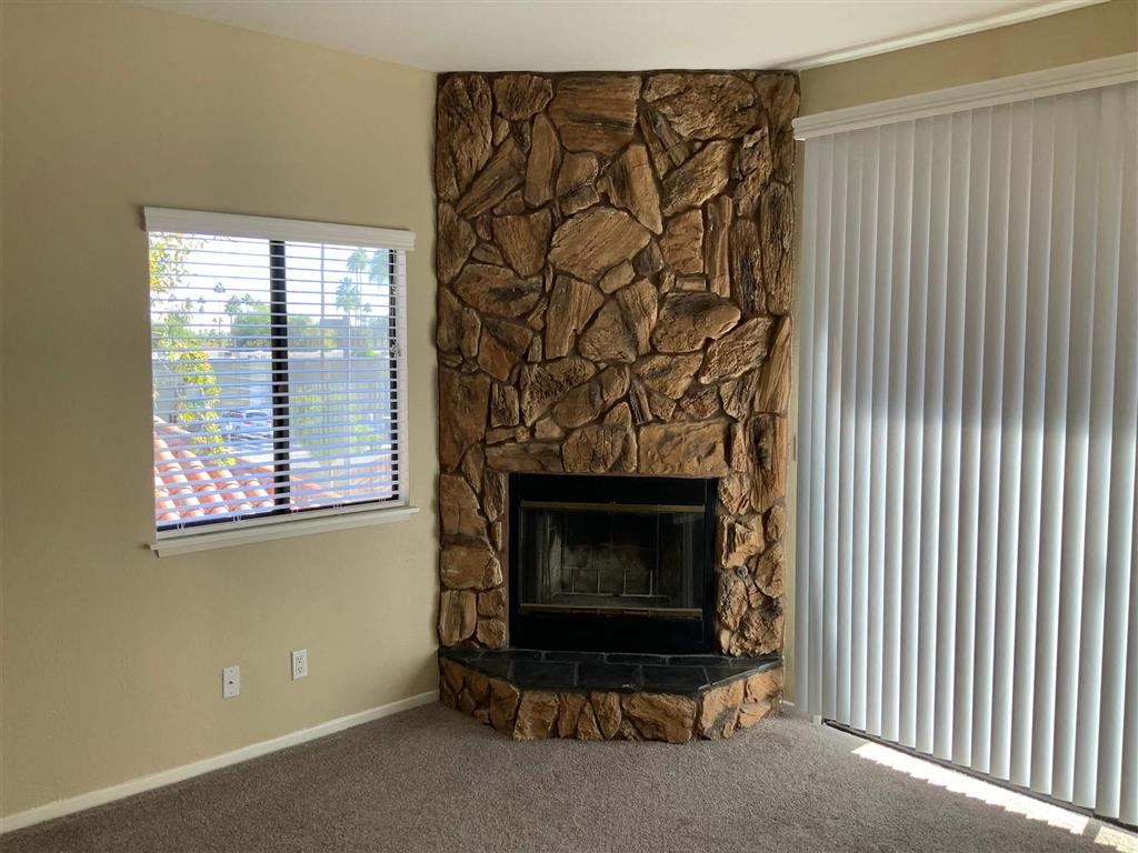 a living room with a stone fireplace and a window