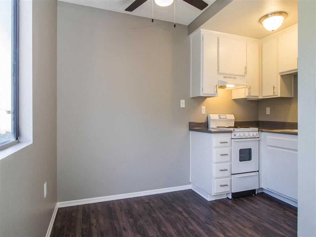 an empty kitchen with white cabinets and a window