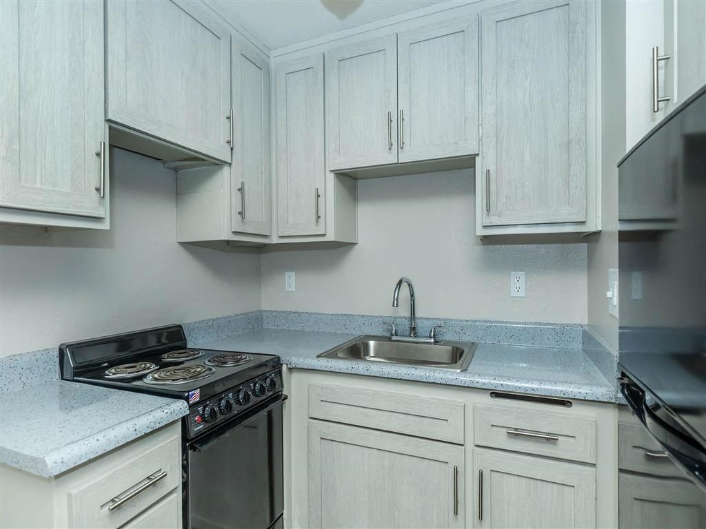 a kitchen with white cabinets and a stove and sink