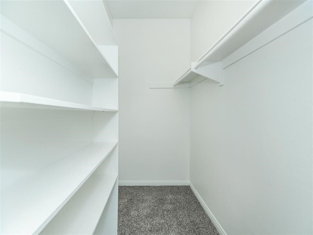 a walk in closet with white walls and shelves