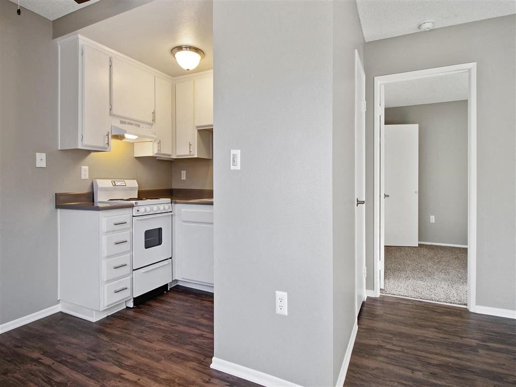 an empty kitchen with white cabinets and a wood floor