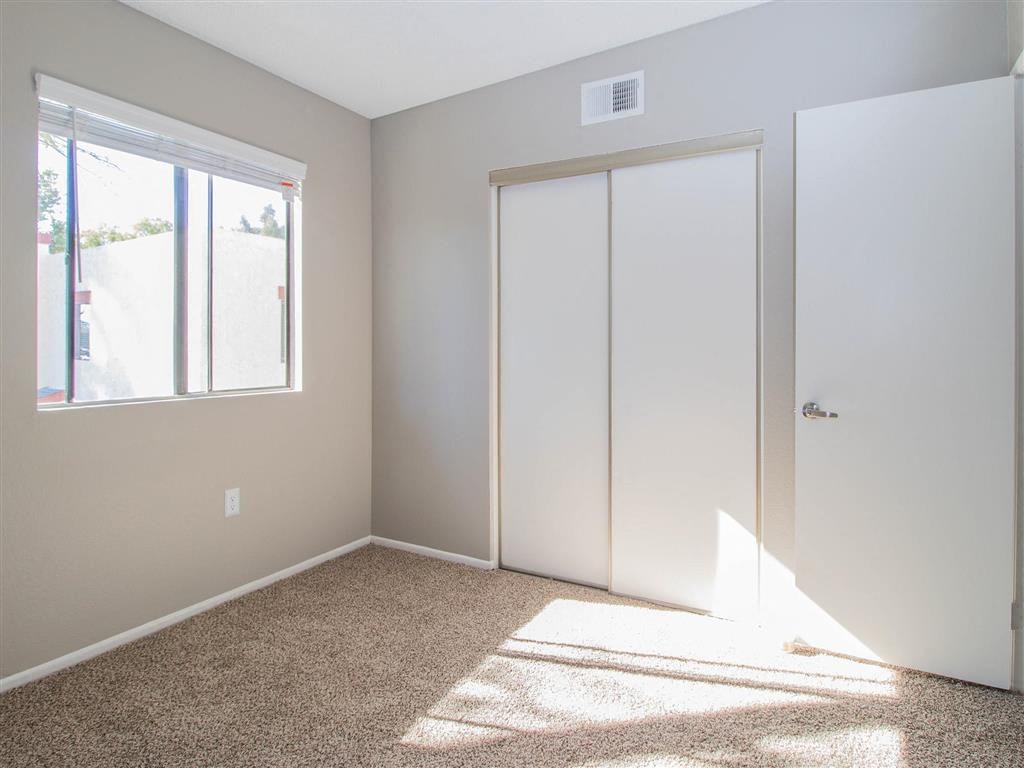 an empty room with a window and white closet doors