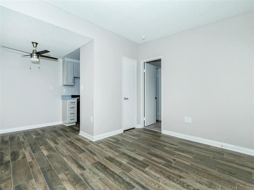 an empty living room with a ceiling fan and a kitchen
