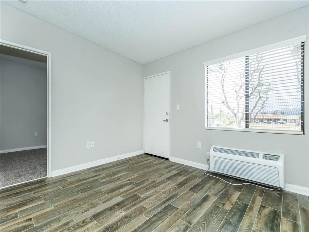 an empty living room with wood flooring and a window