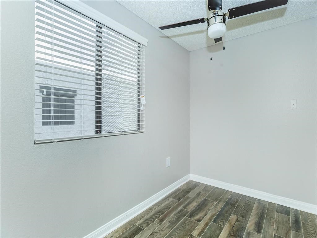 an empty room with a window and a ceiling fan