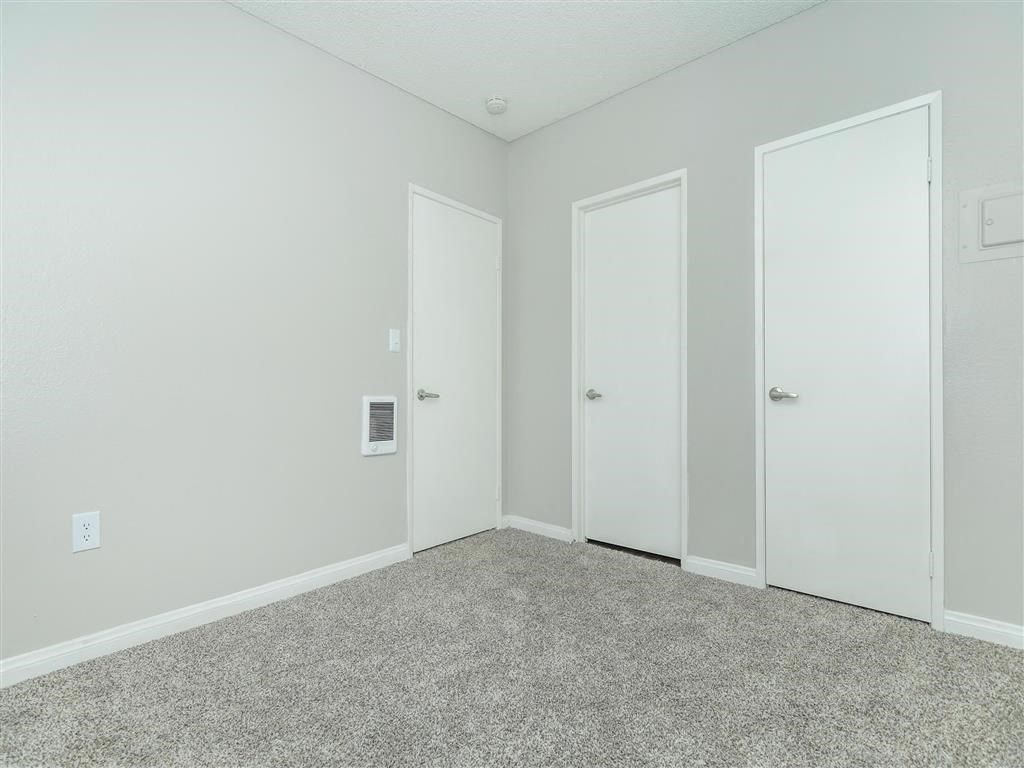 a bedroom with two doors and a carpeted floor