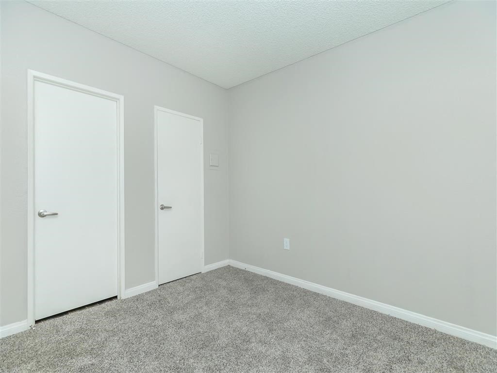 a bedroom with a carpeted floor and two doors