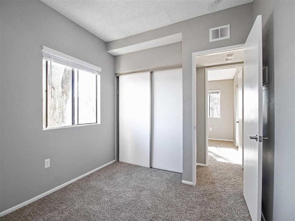 an empty bedroom with a door to a closet and a window
