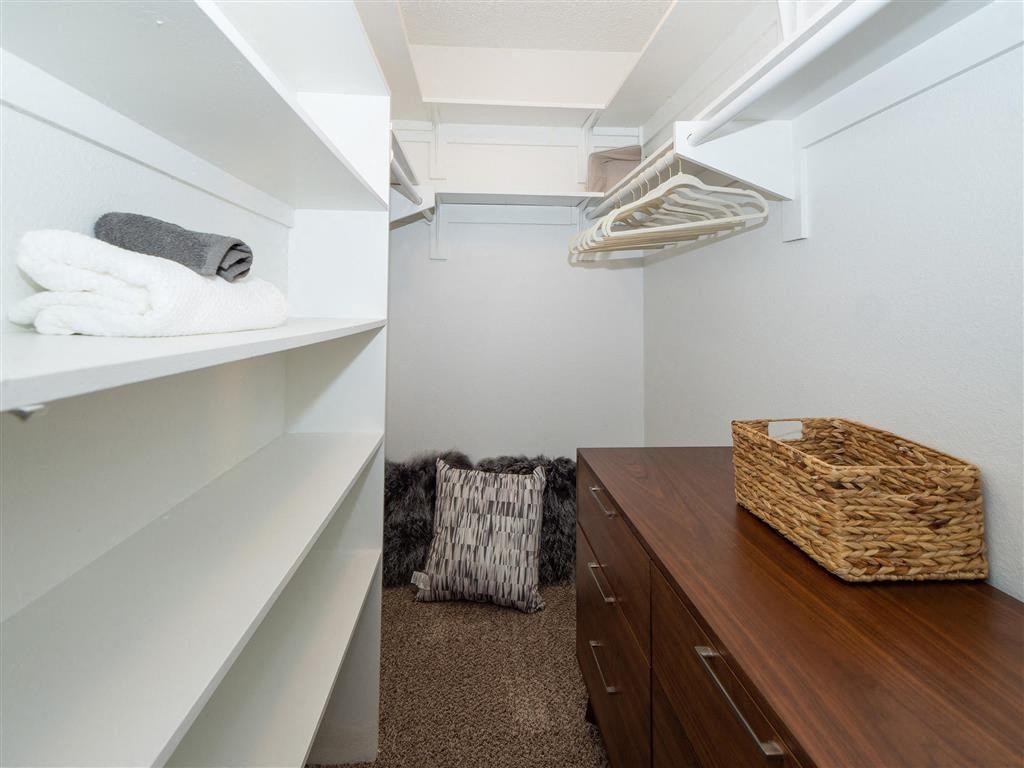 a walk in closet with shelves and a basket