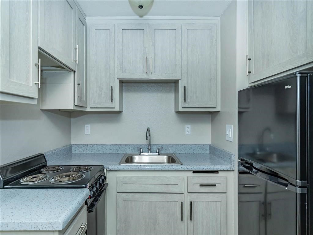 a kitchen with white cabinets and a stove and sink
