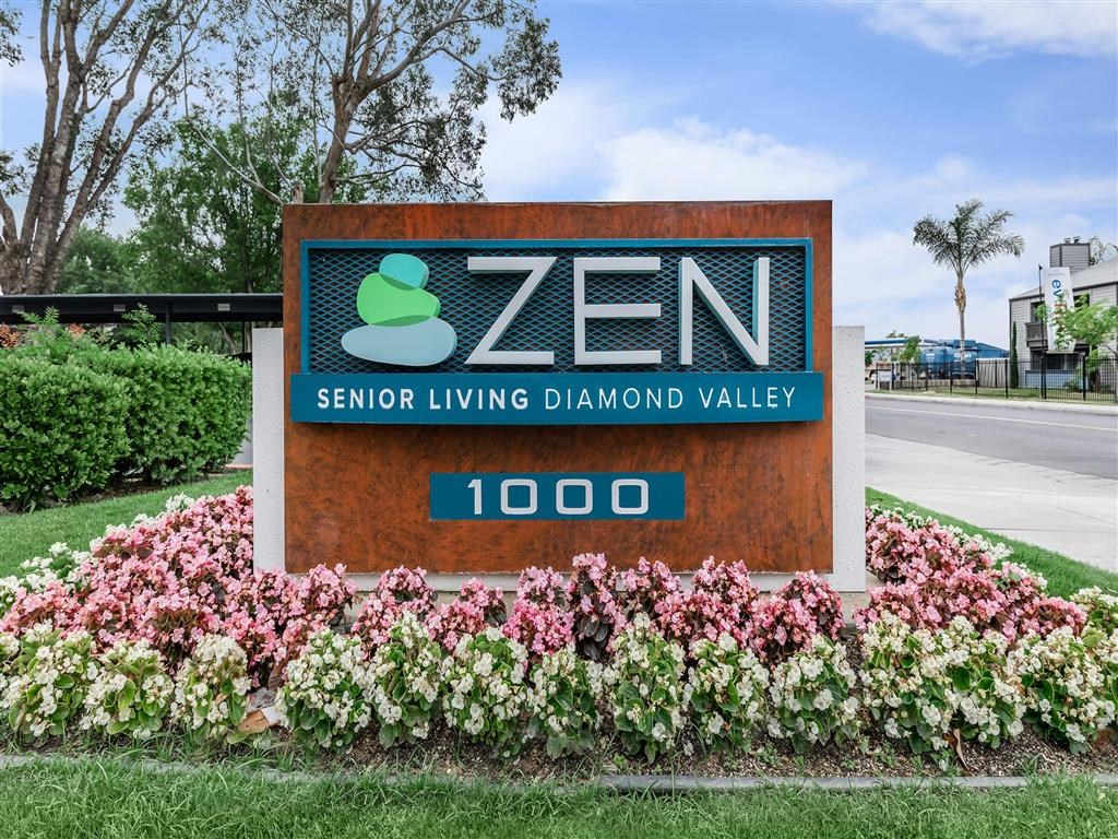a sign for zen senior living diamond valley in front of flowers