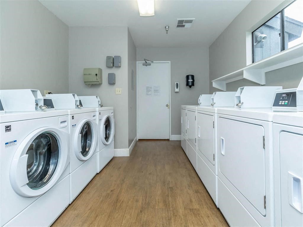 a laundry room with washers and dryers and a row of washing machines