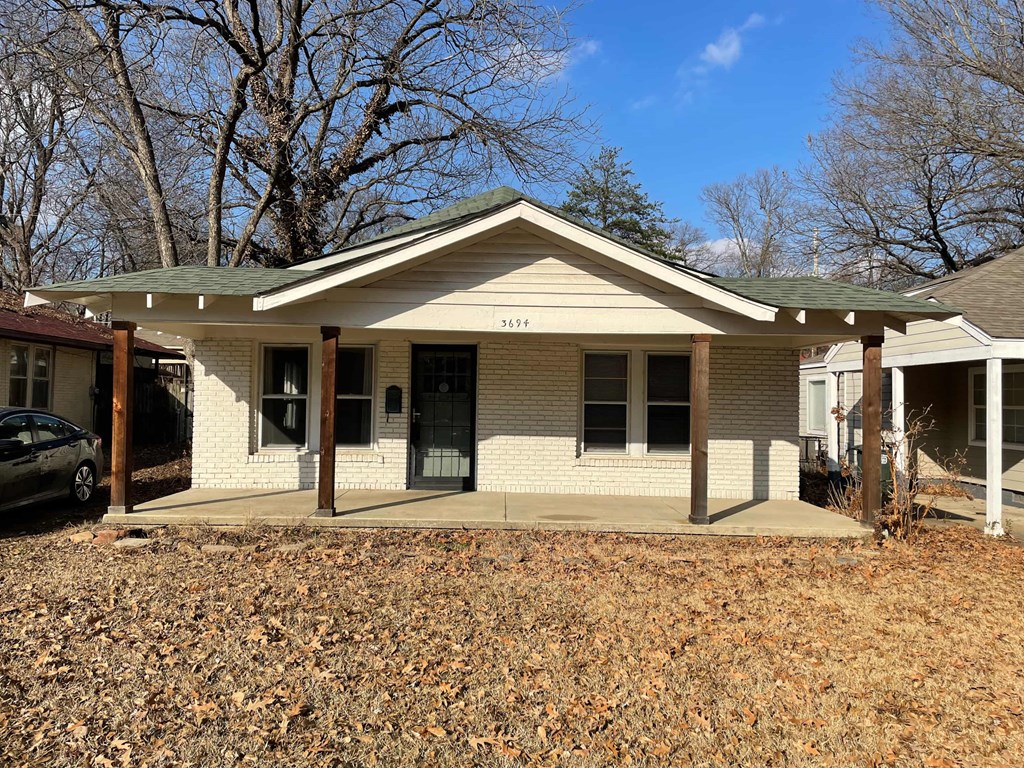 a white brick house with a porch and a car in front of it