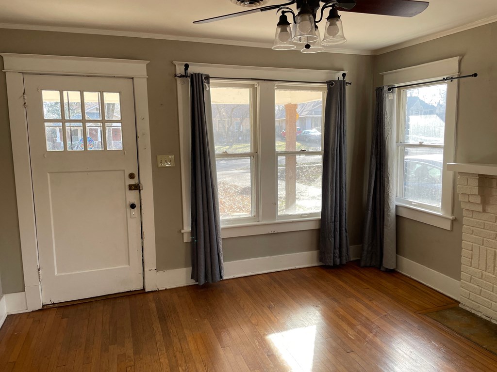a living room with two windows and a door with curtains