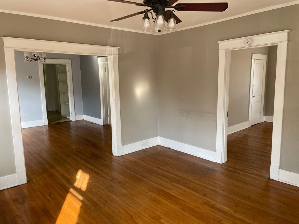 an empty living room with wood floors and a ceiling fan