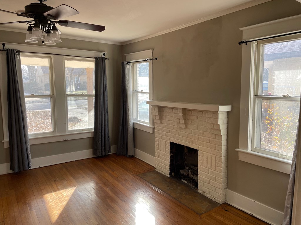 a living room with a brick fireplace and two windows