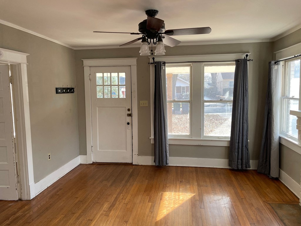 an empty living room with a ceiling fan and windows