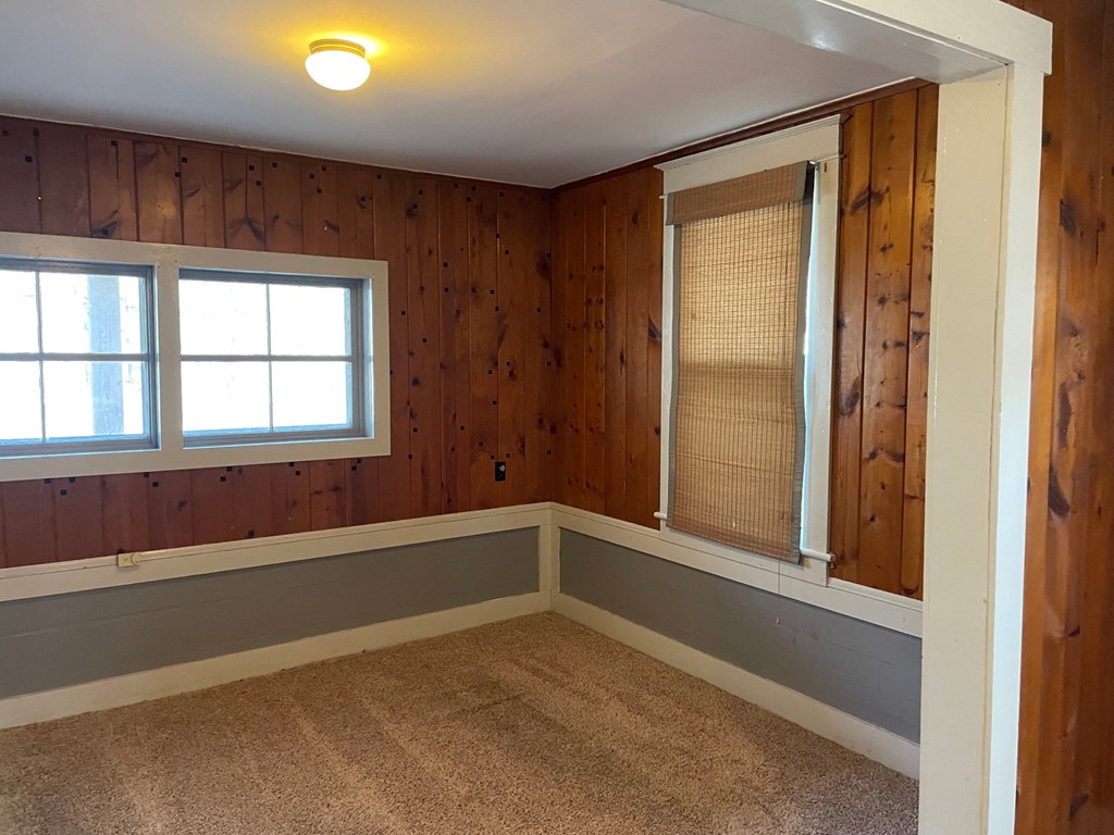 the corner of a room with wood paneled walls and a window