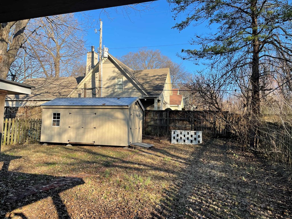 a backyard with a shed and a fence and a house