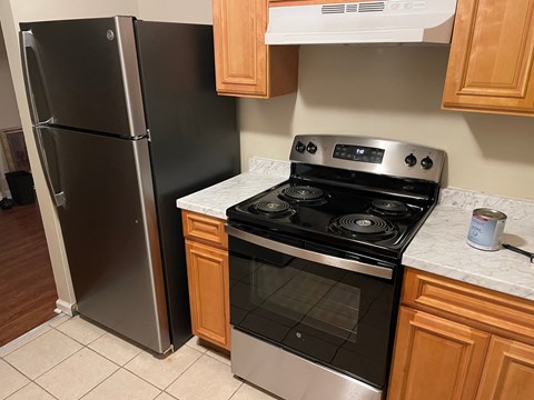 A black refrigerator stands next to a stove in a kitchen.