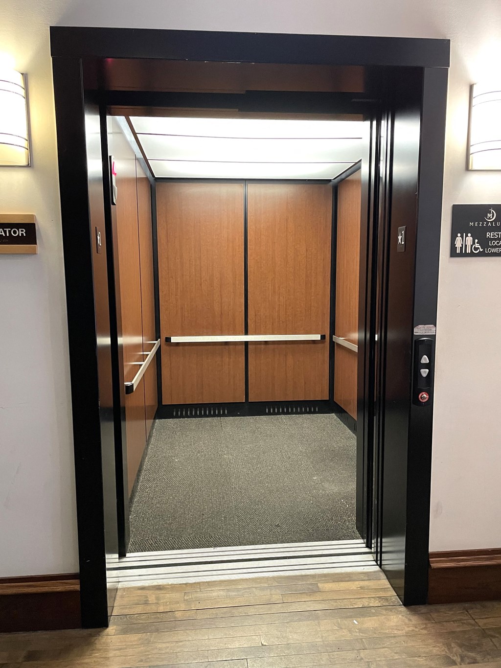 an open elevator with wood paneled walls and a carpeted floor