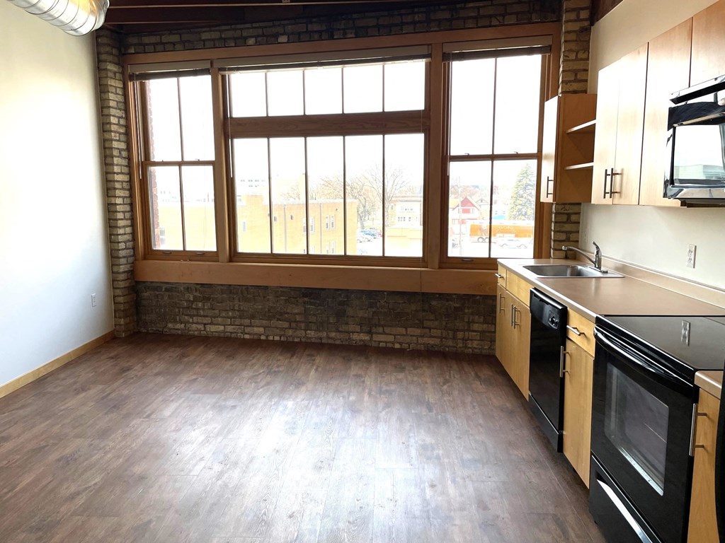 an empty kitchen with wood floors and large windows