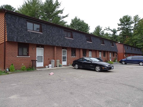 A black car is parked in front of a brick building.