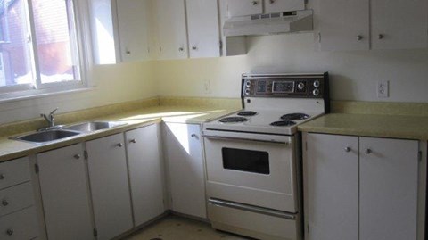 A white kitchen with a stove and sink.