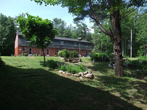 A red house with a green lawn in front of it.