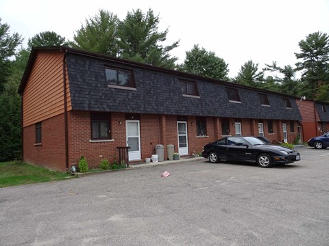 A black car is parked in front of a brick building.