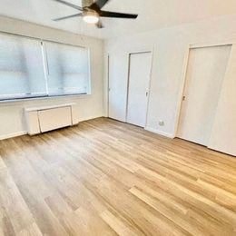 an empty living room with wood floors and a ceiling fan