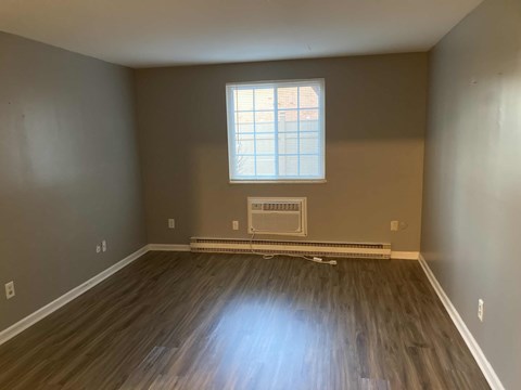 A room with a window and a radiator on the floor.