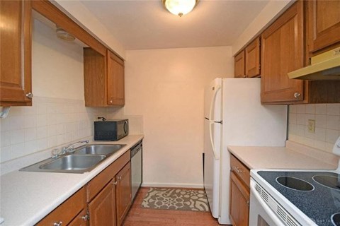 A kitchen with wooden cabinets and a white fridge.