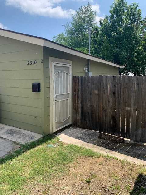a house with a white door next to a wooden fence