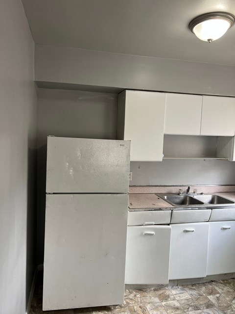 A white refrigerator and cabinets in a kitchen.