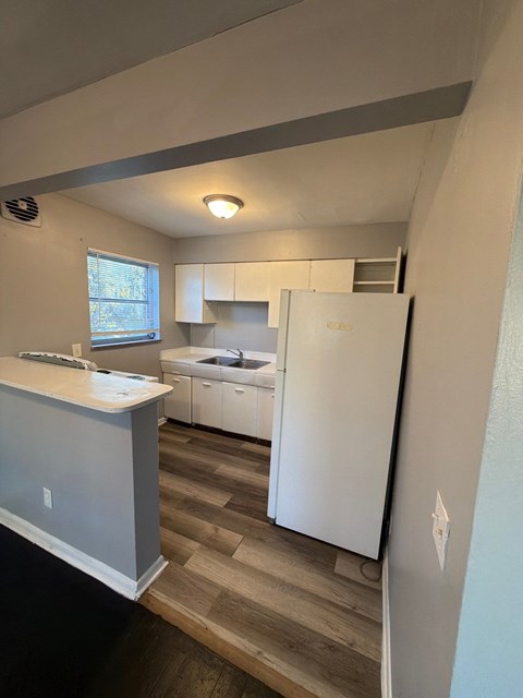 A kitchen with a white fridge and a window.