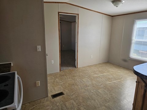 A room with a doorway leading to another room and a window on the right side.