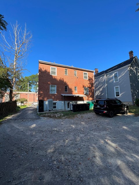 A black car is parked in front of a brick building.