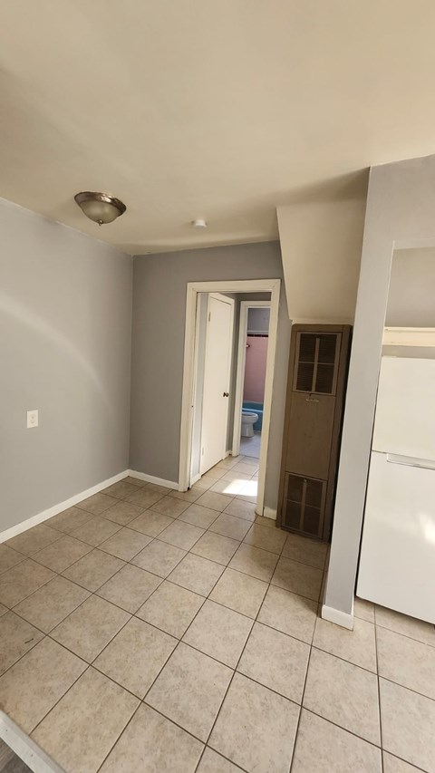 A kitchen area with a white refrigerator and a doorway leading to another room.