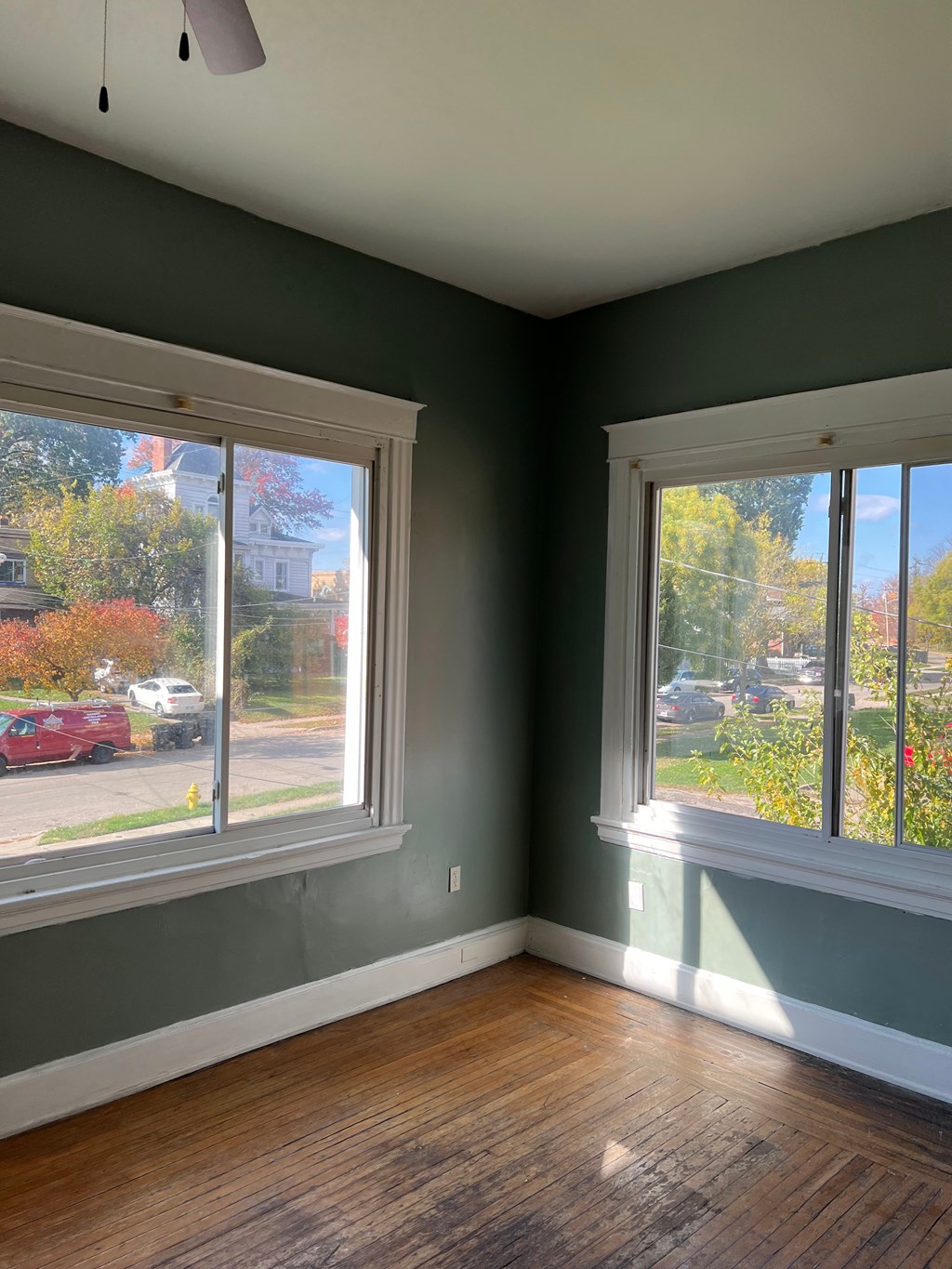 A room with two windows and wooden floors.