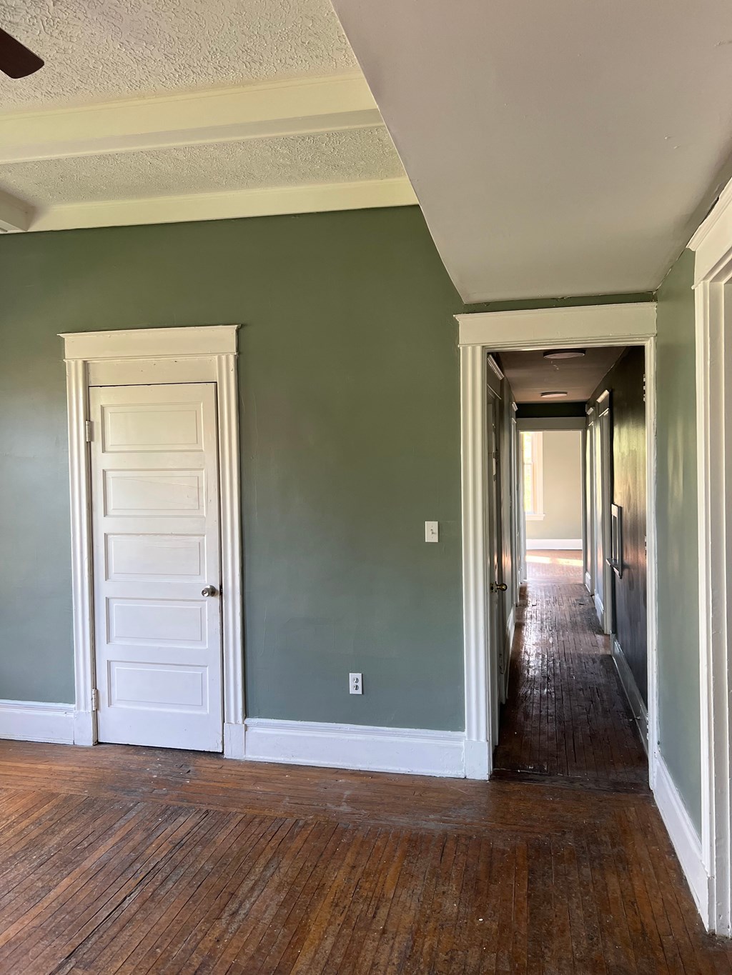 A long hallway with a white door on the left and a white door on the right.