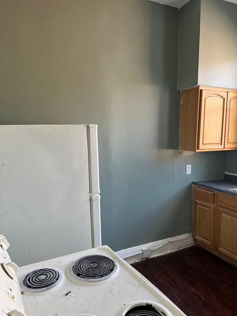 A white stove is in a kitchen with a blue wall.