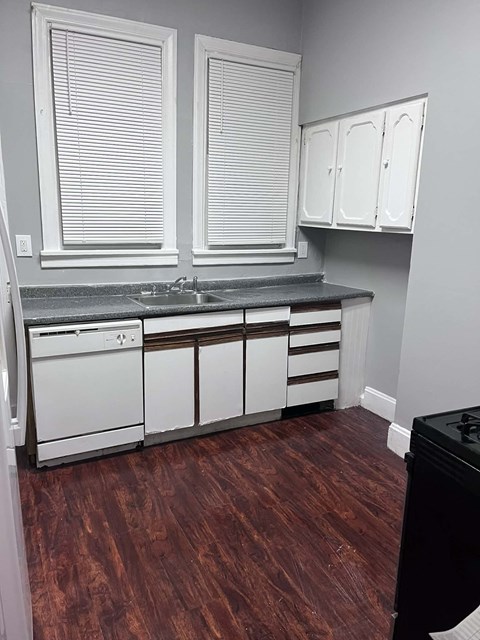 A kitchen with white cabinets and a black dishwasher.