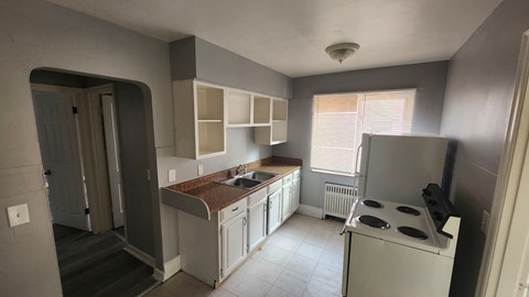 A kitchen with white cabinets and a brown countertop.