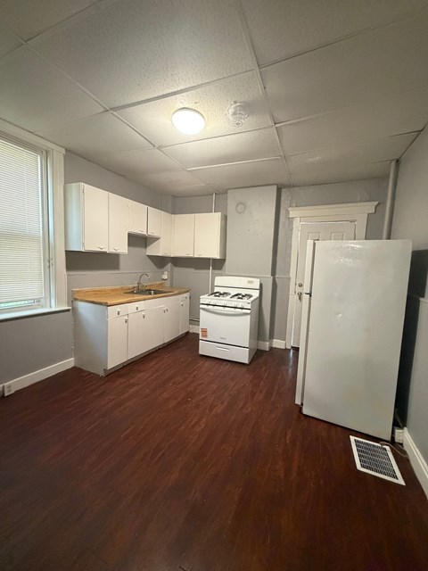 A kitchen with white appliances and wooden floors.