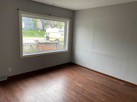 a living room with a large window and wooden floors