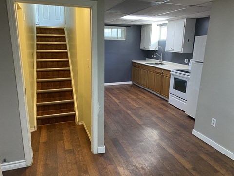 a view of a kitchen and stairs from the living room with a stove and sink