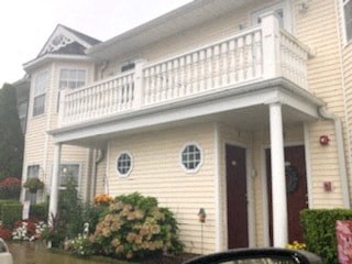 a yellow house with a white balcony on top of it