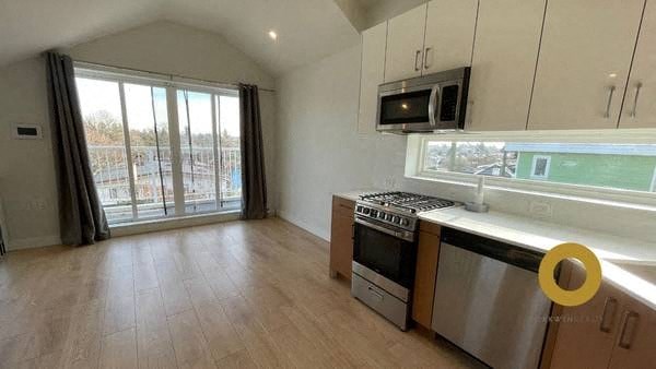 a kitchen with a stove and a microwave and a window