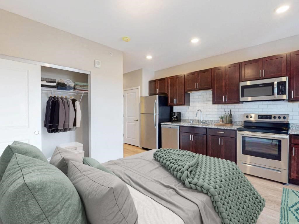 a living room with a couch and a kitchen with stainless steel appliances